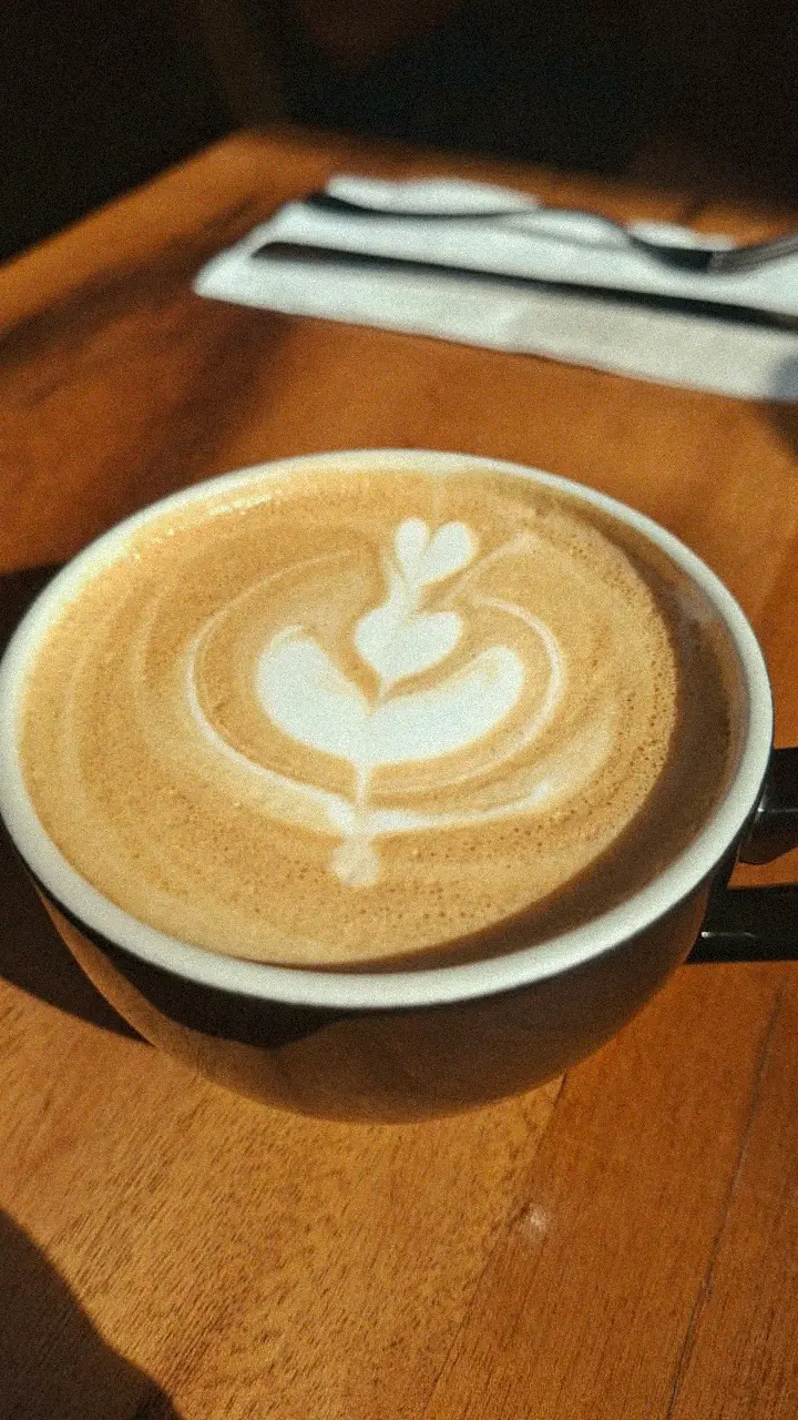Detalhe de uma arte de latte em uma caneca preta sobre uma mesa de madeira