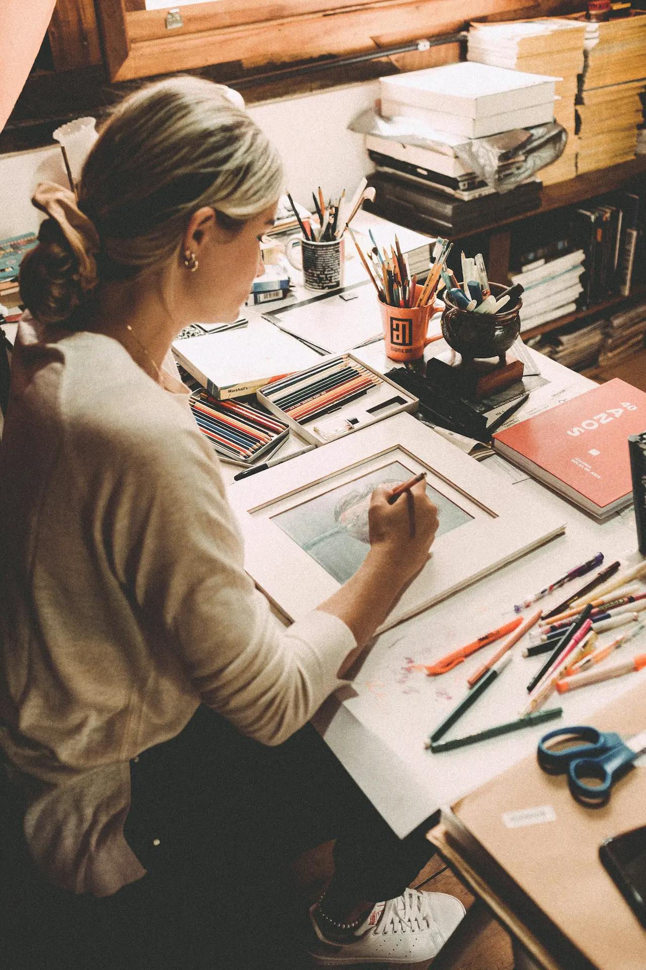 over the shoulder shot of a woman drawing in her studio desk